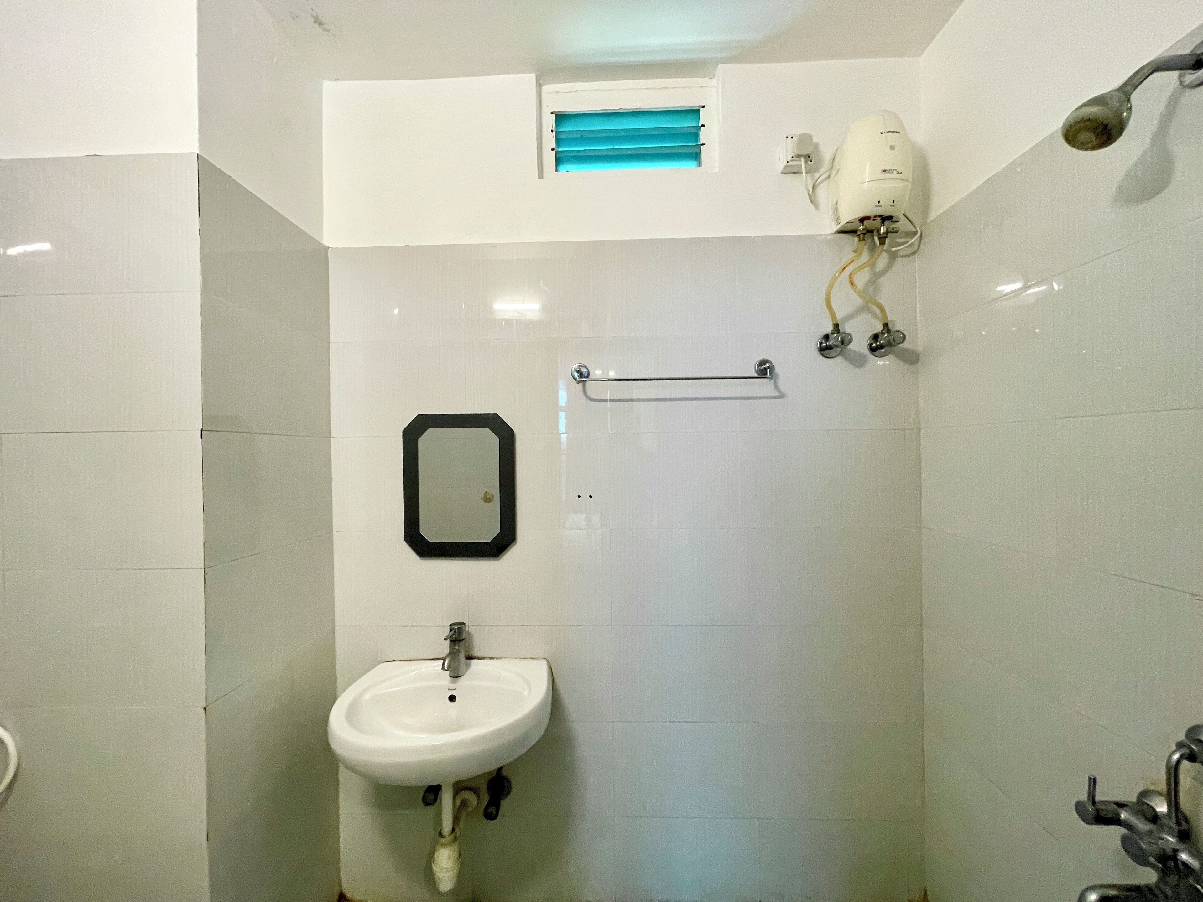 A bathroom with a white sink, a mirror, a towel rack, and a showerhead.