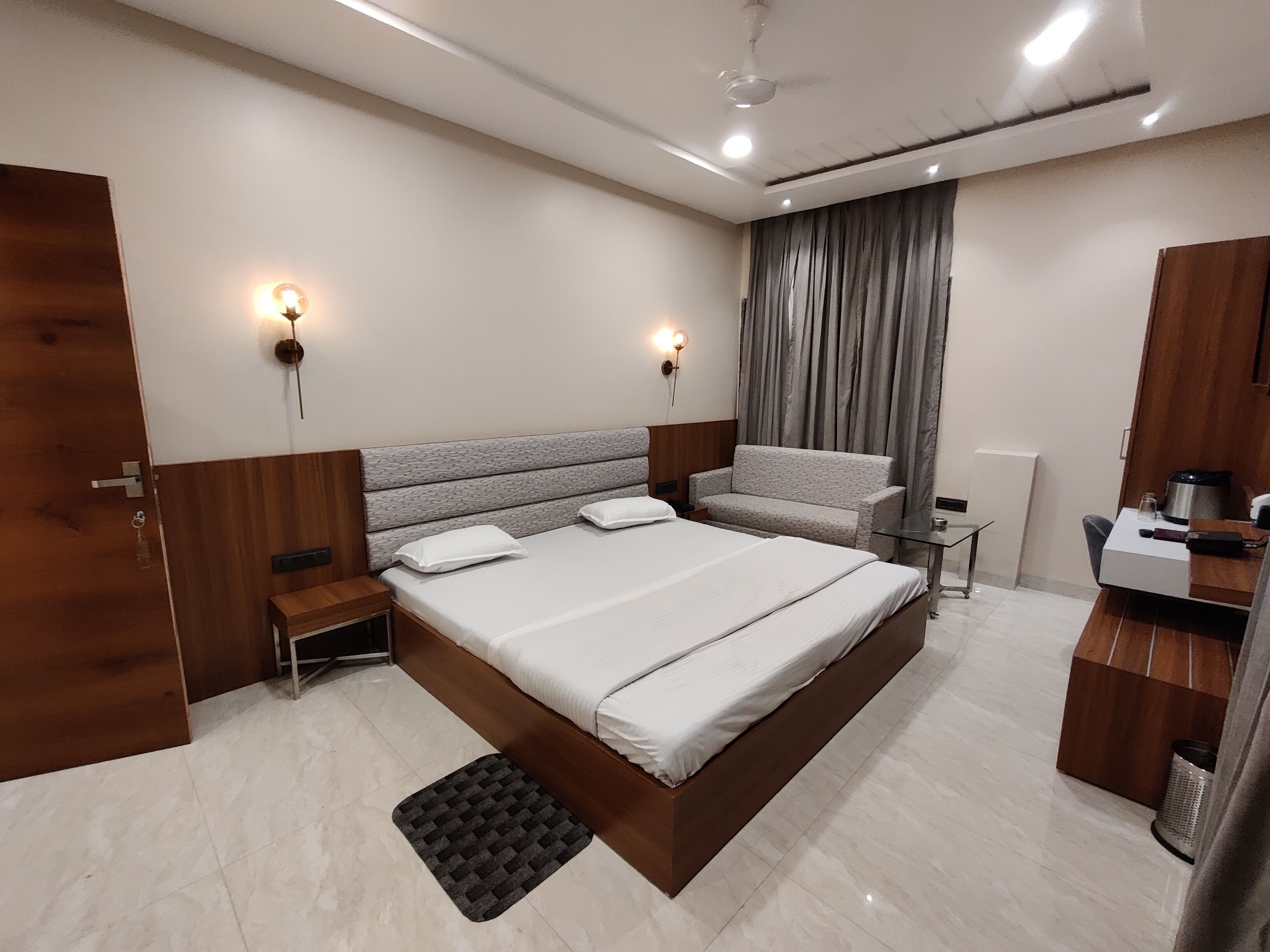 Un dormitorio moderno con una cama grande, mesitas de noche, un sofá, un escritorio y un ventilador de techo.