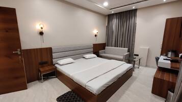 Un dormitorio moderno con una cama grande, mesitas de noche, un sofá, un escritorio y un ventilador de techo.