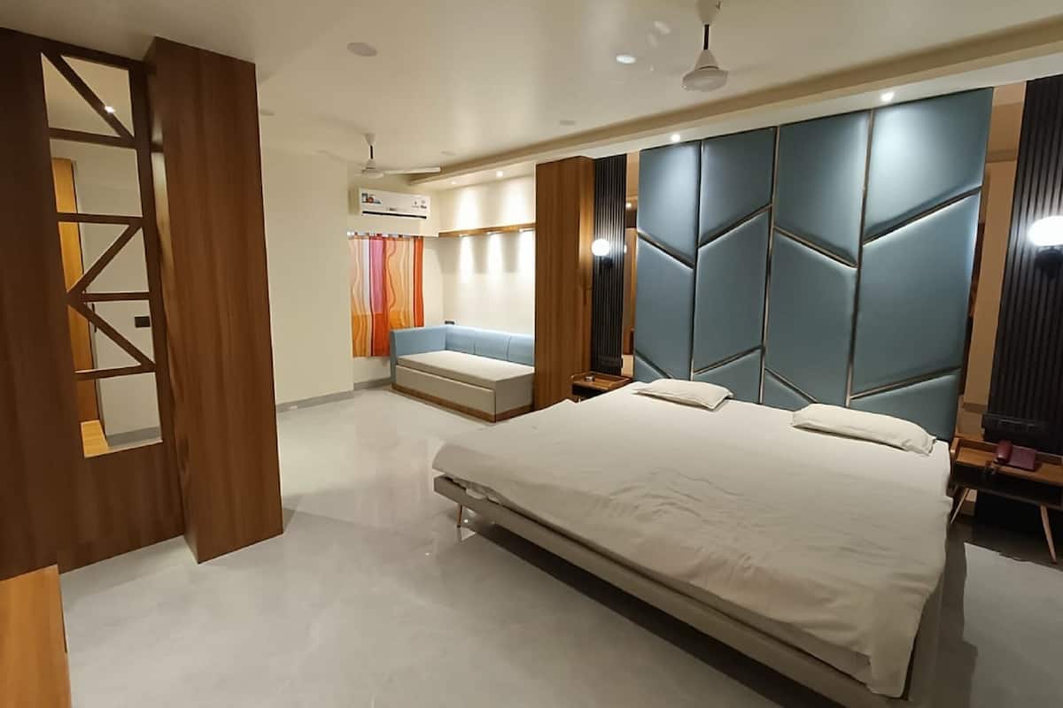Een moderne slaapkamer met een groot bed, een inbouwkbank en een decoratief wandpaneel.