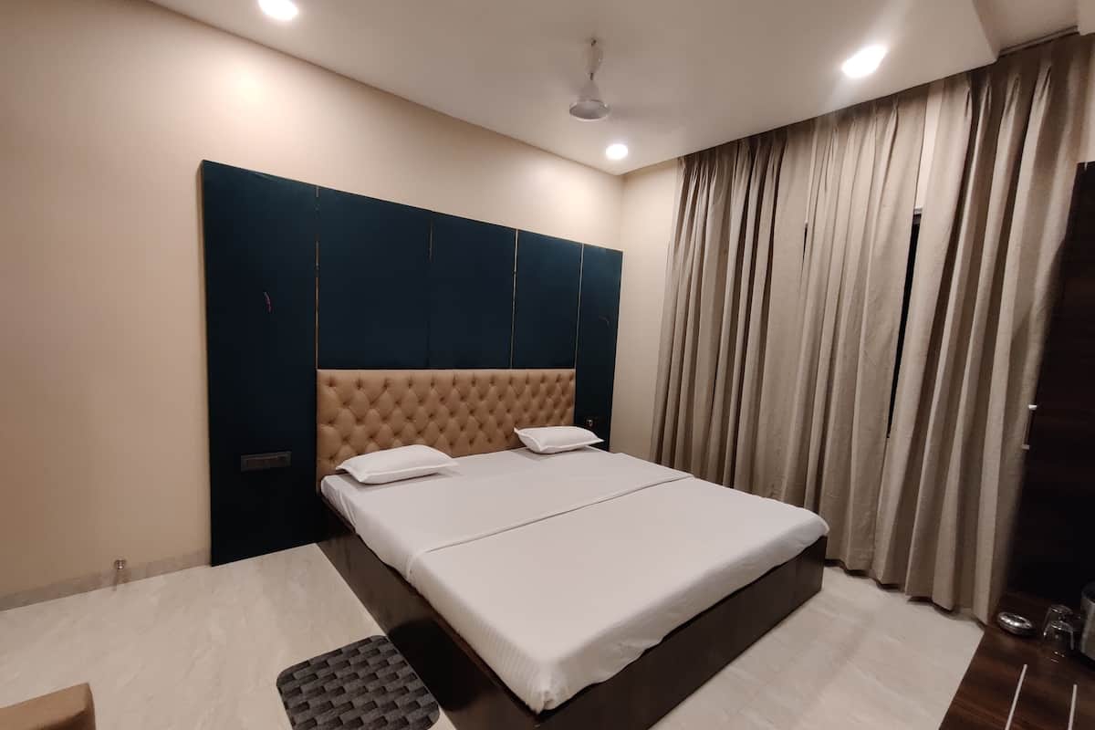 Een moderne hotelkamer met een groot bed, een hoofdbord, een nachtkastje en een raam met gordijnen.