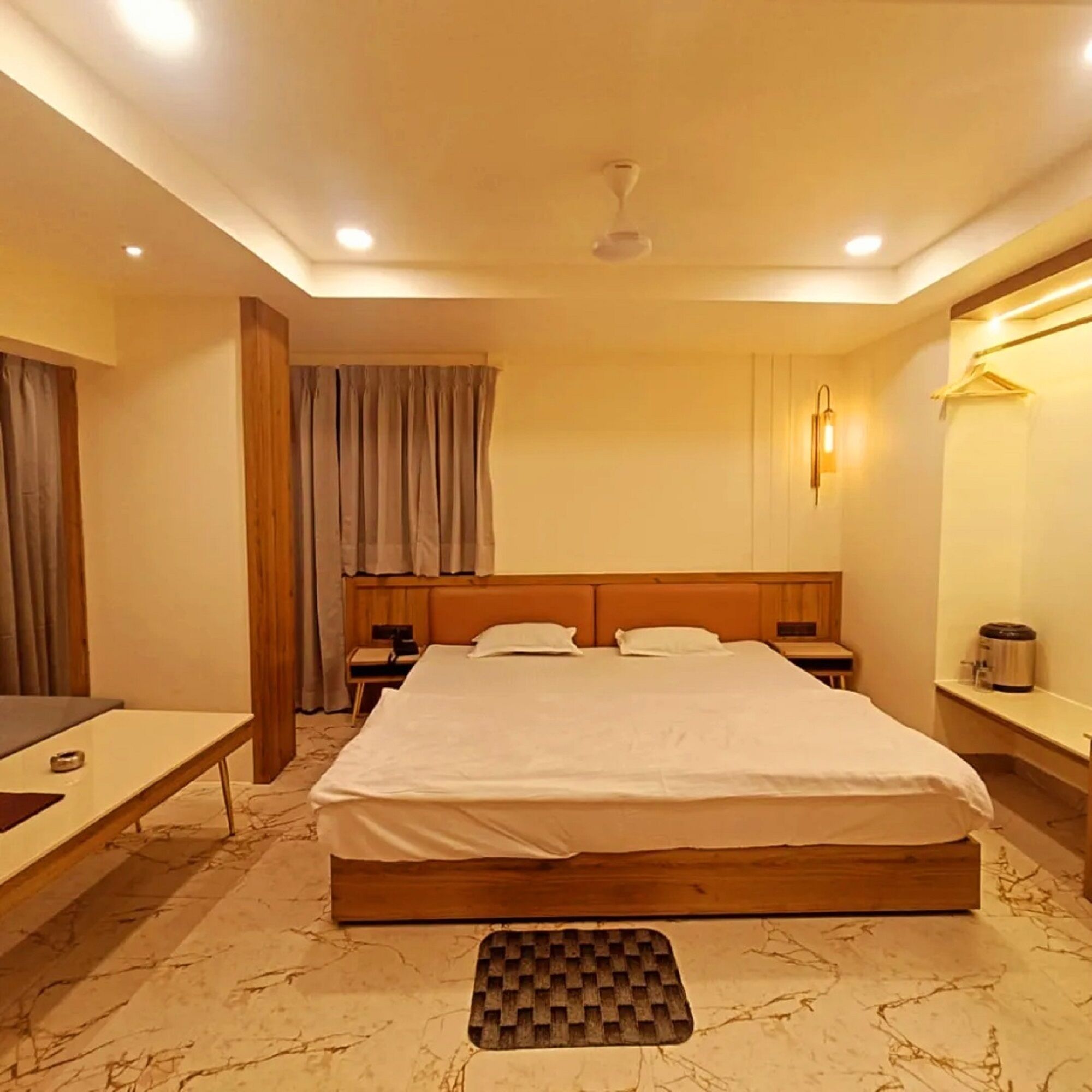 A hotel room with a large bed, bedside tables, a desk, and a chair.