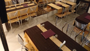Zona pranzo con diversi tavoli e sedie disposti a griglia.