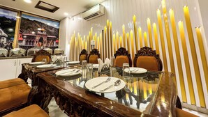 A dining area with a long wooden table, chairs, and candles. - Arogyadham Wellness Retreat (Rishikesh)