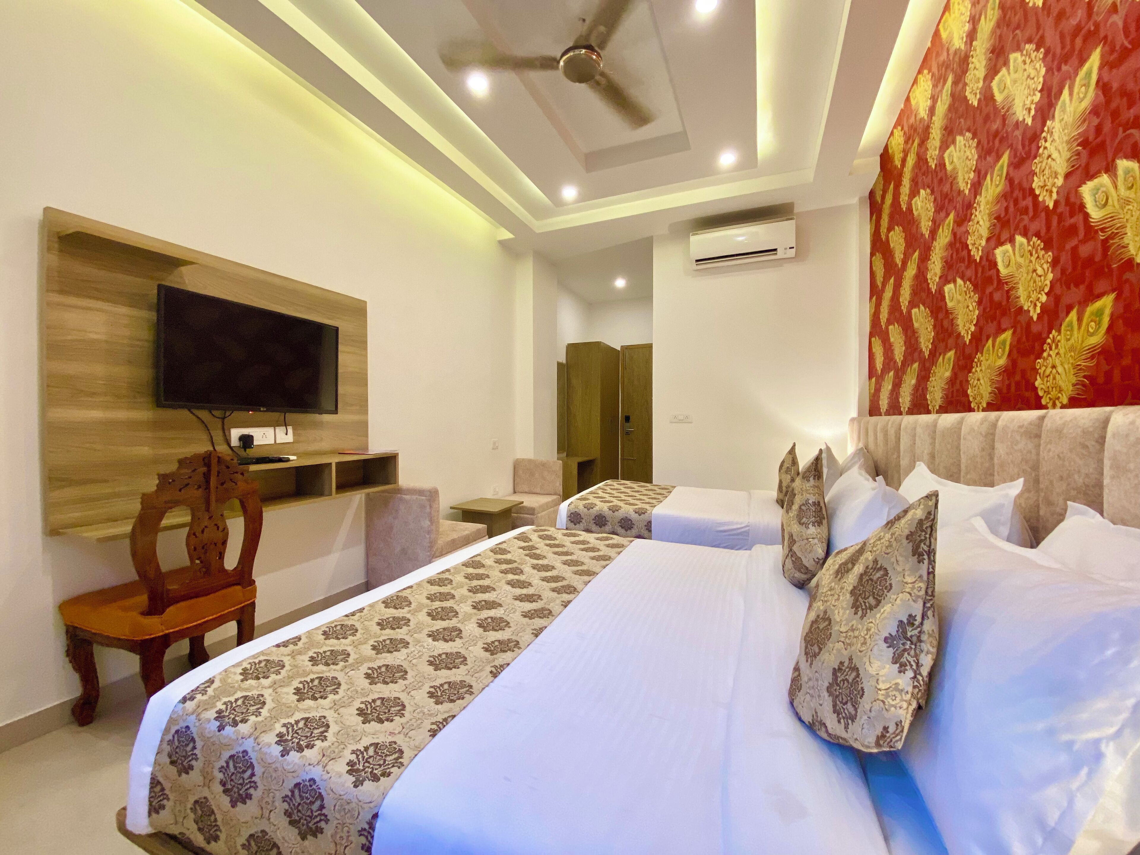 A hotel room with a bed, a TV, a desk, a chair, and a wardrobe.