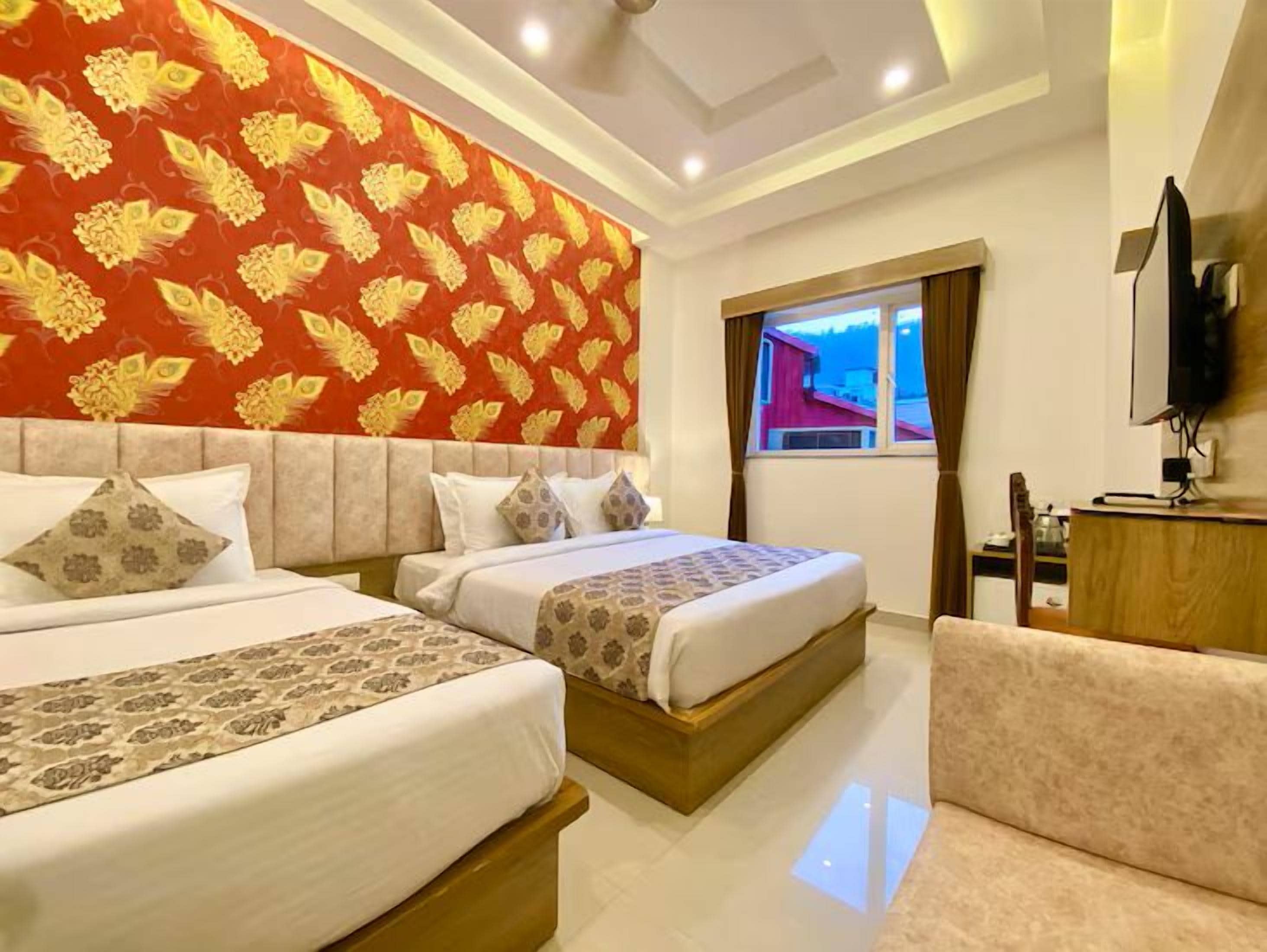 A hotel room with two beds, a TV, and a window with curtains.