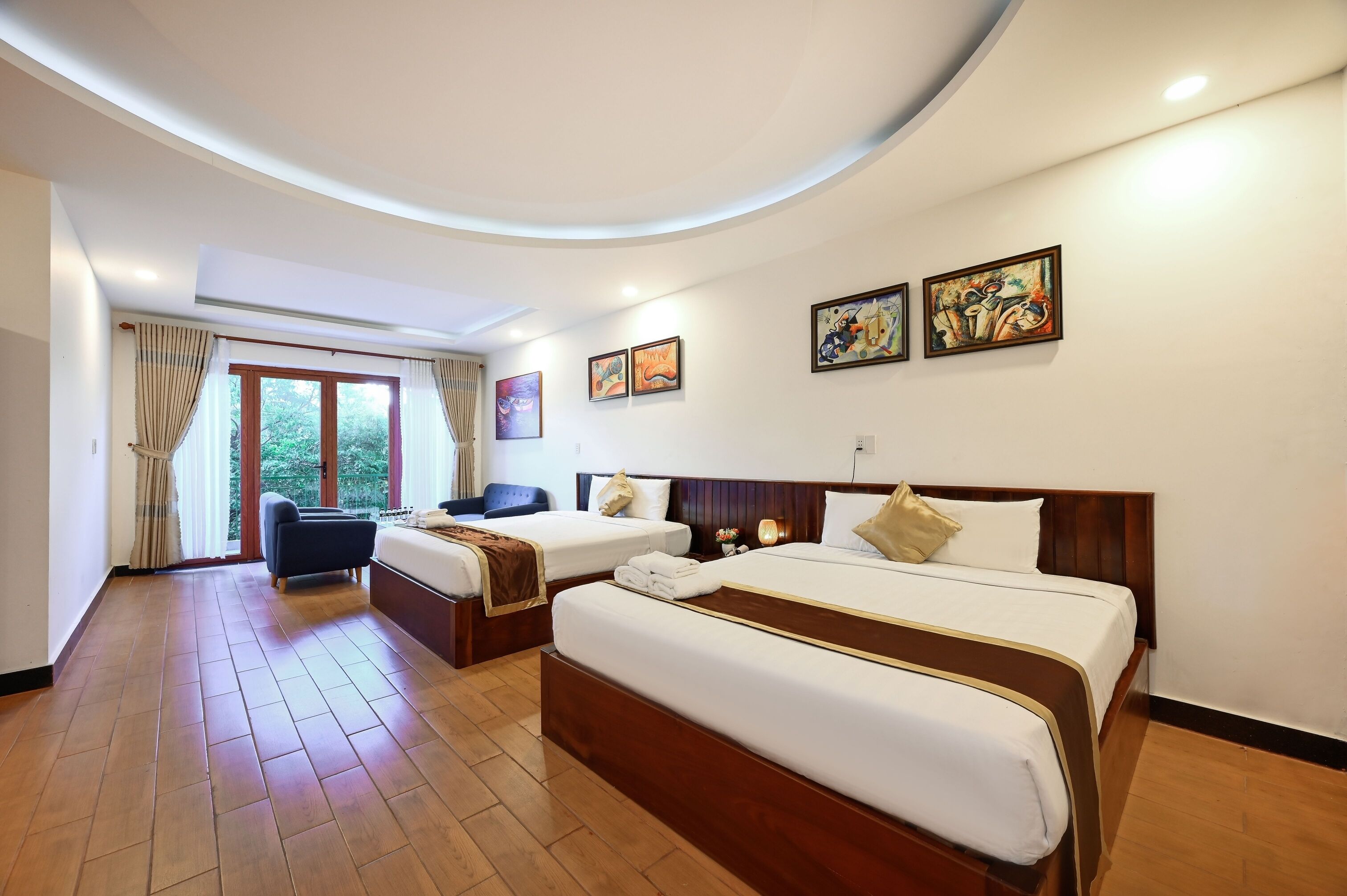 Habitación de hotel con dos camas, un sofá y un amplio ventanal con cortinas.