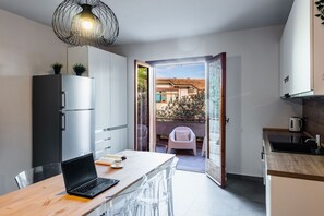 Una cocina moderna con comedor, una computadora portátil sobre la mesa y vistas al balcón exterior.