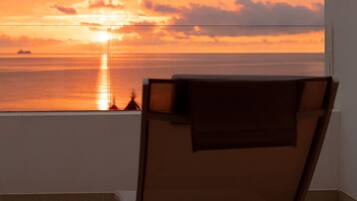 Una silla reclinable con vistas a la puesta de sol sobre el océano.