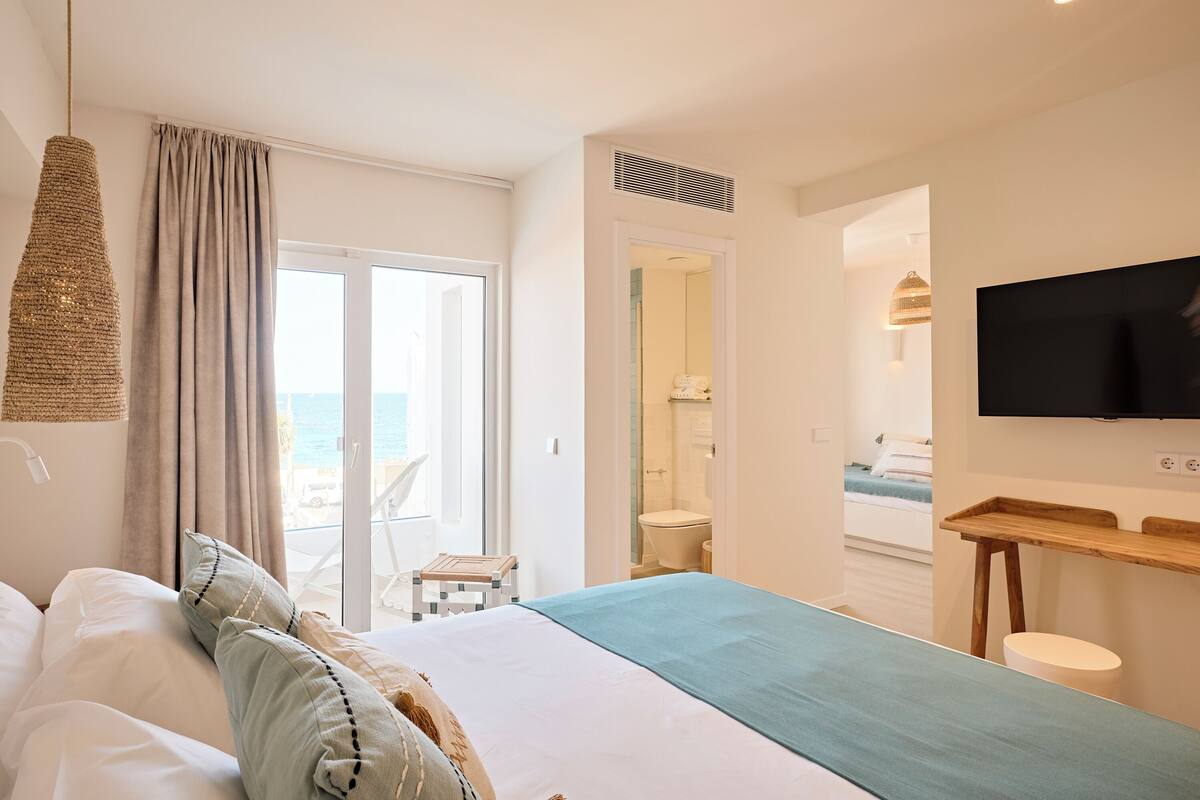 Ein Hotelzimmer mit Bett, Fernseher, Schreibtisch und Meerblick.