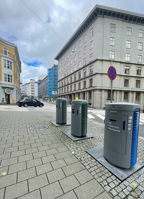 Een straat met een parkeerverbod, een gebouw met veel ramen, en twee airconditioners op de stoep.