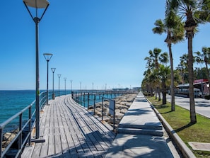 A wooden boardwalk leading to a pier with street lamps and palm trees. - Sanders Premier Downtown - Full Building (Limassol)