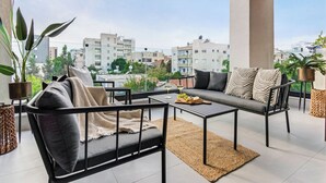 Un balcón con sofá, sillas y una mesa, que ofrece vistas a la ciudad.
