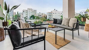 A balcony with a sofa, chairs, and a table, featuring a city view. - Sanders Premier Downtown - Full Building (Limassol)