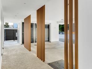 A modern hallway with a concrete floor, wooden vertical panels, and a metal door with a parking sign. - Sanders Premier Downtown - Full Building (Limassol)