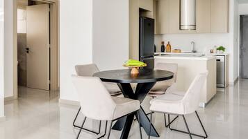 Una cocina moderna con una isla central, una mesa de comedor con sillas y un ventanal grande.