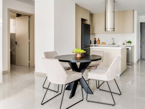A modern kitchen with a central island, a dining table with chairs, and a large window. - Sanders Premier Downtown - Full Building (Limassol)