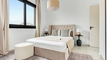 Un dormitorio moderno con una cama grande, dos mesitas de noche, una lámpara colgante y vistas de la ciudad a través de un ventanal.