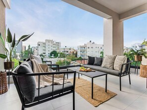 A balcony with a sofa, chairs, and a table, featuring a city view. - Sanders Premier Downtown - Full Building (Limassol)