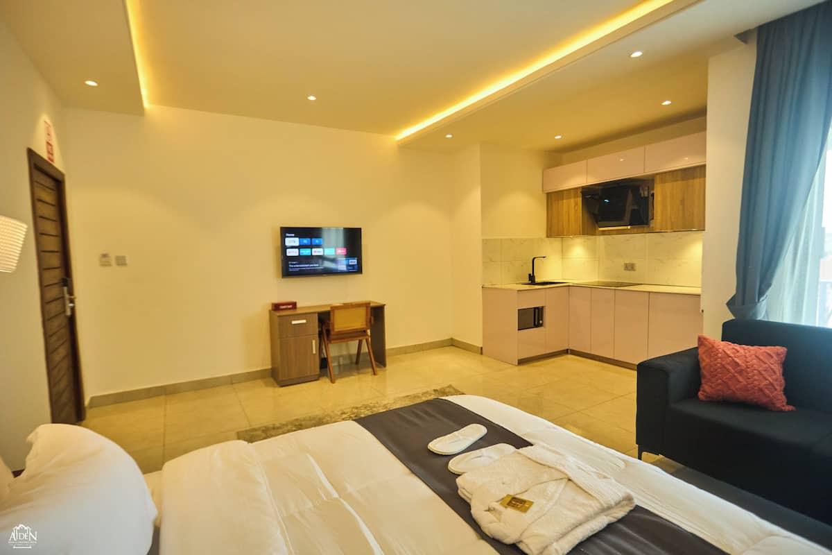 Ein modernes Hotelzimmer mit Bett, Schreibtisch, Fernseher und einer Küchenzeile.