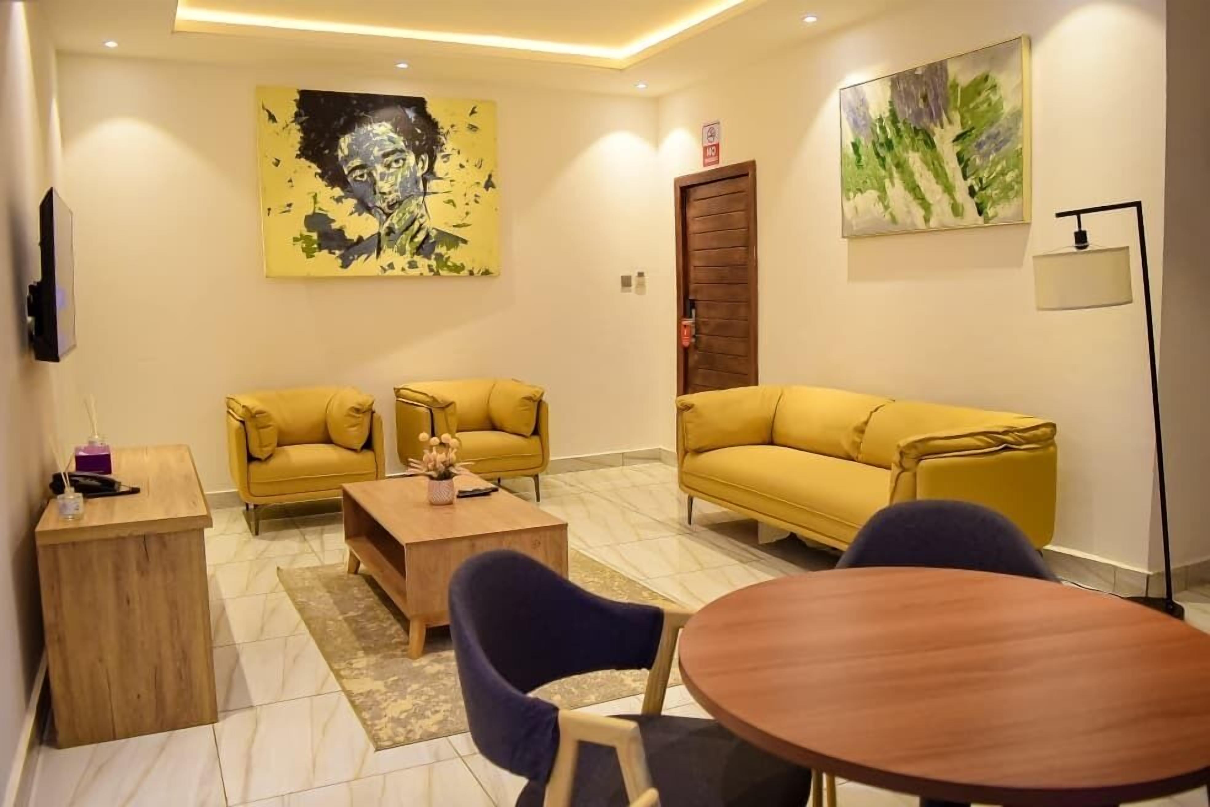 A modern living room with two yellow sofas, a wooden coffee table, and a round table with chairs.