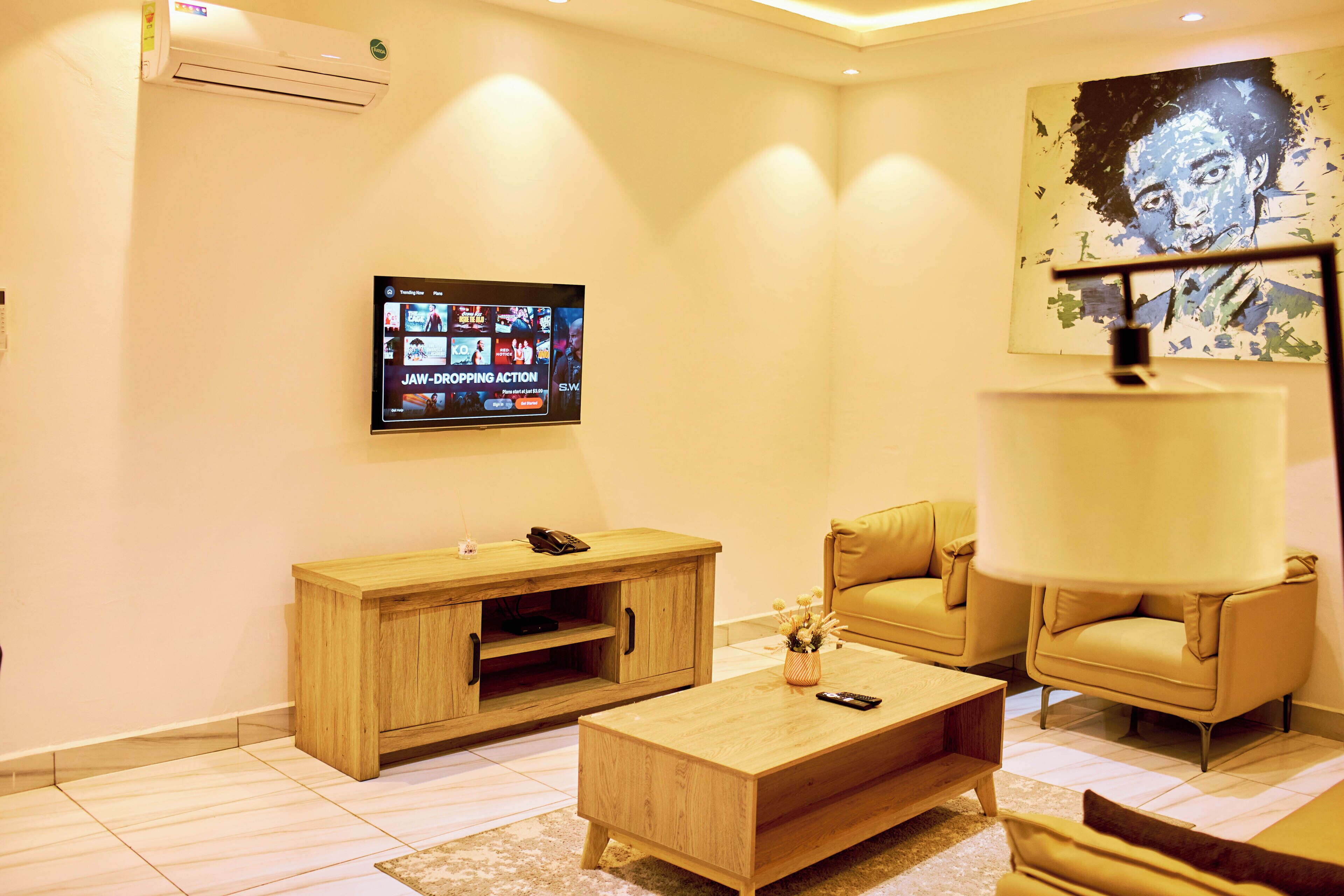 A living room with a TV, sofa, armchair, coffee table, and a painting on the wall.