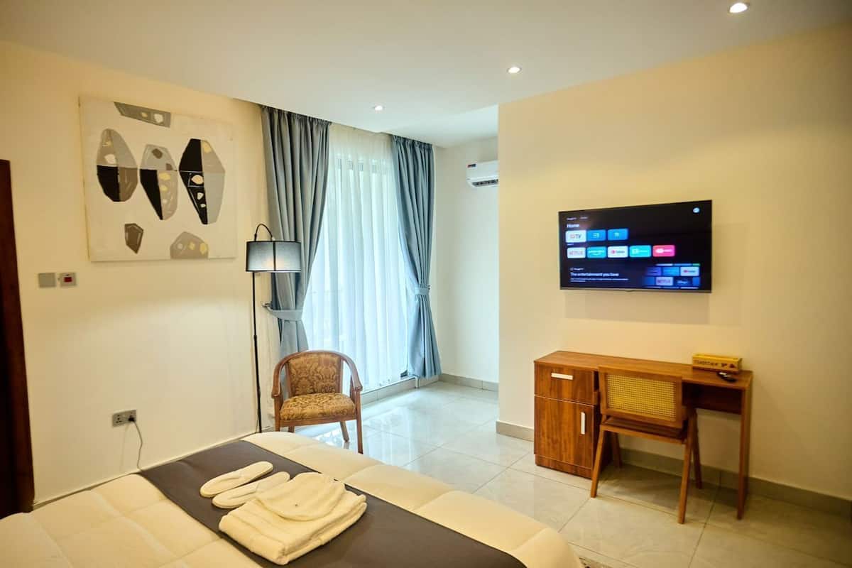 Ein Hotelzimmer mit Bett, Schreibtisch, Fernseher und Stuhl.