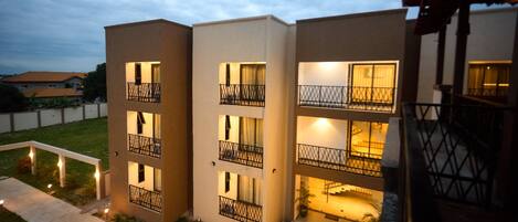 A modern multi-story building with balconies and exterior lighting.
