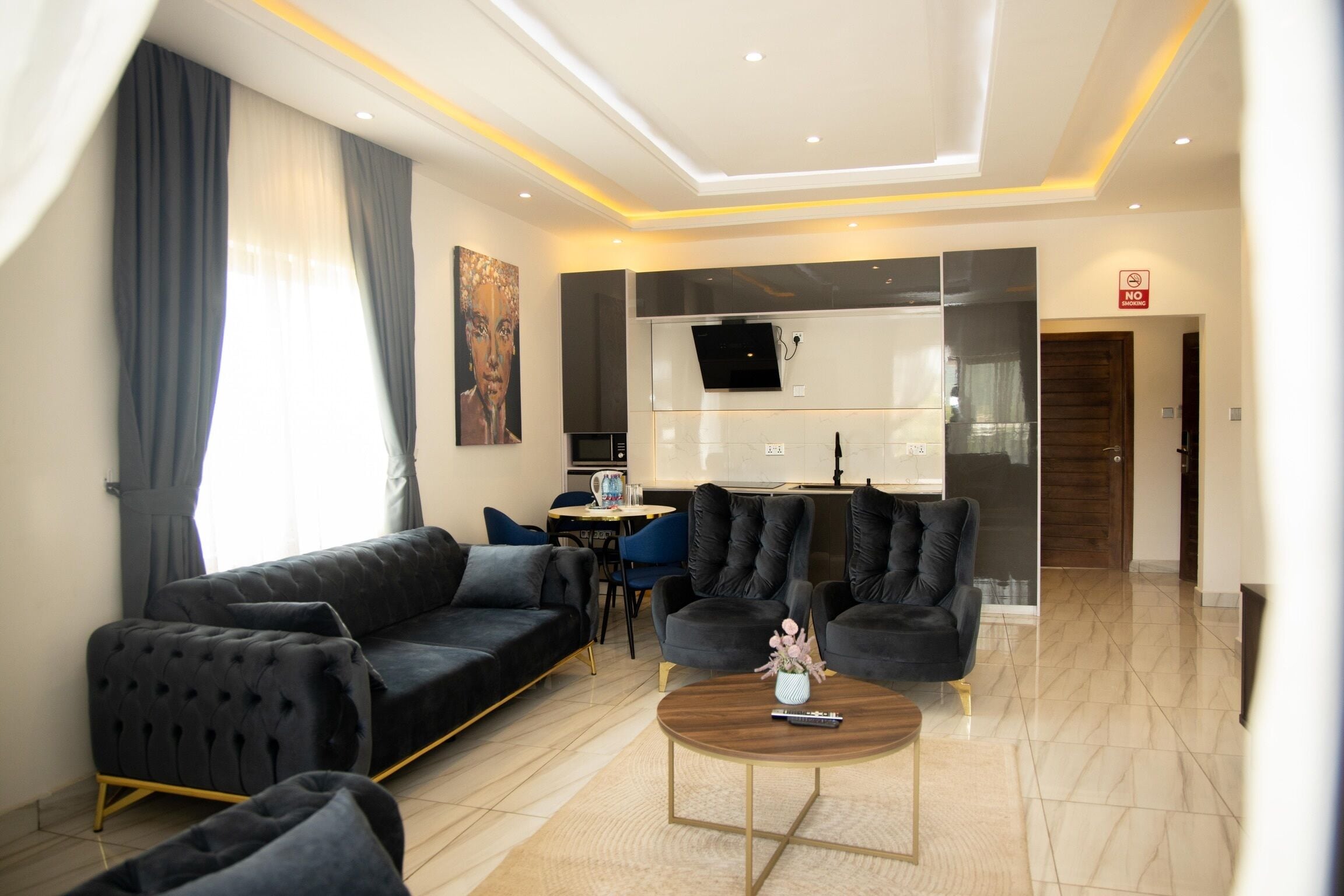 Un salon moderne avec un canapé noir, une table basse et un téléviseur fixé au mur.