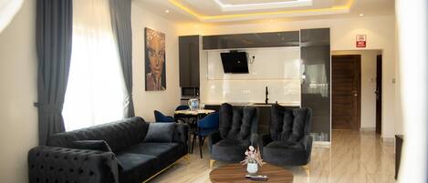 Un salon moderne avec un canapé noir, une table basse et un téléviseur fixé au mur.