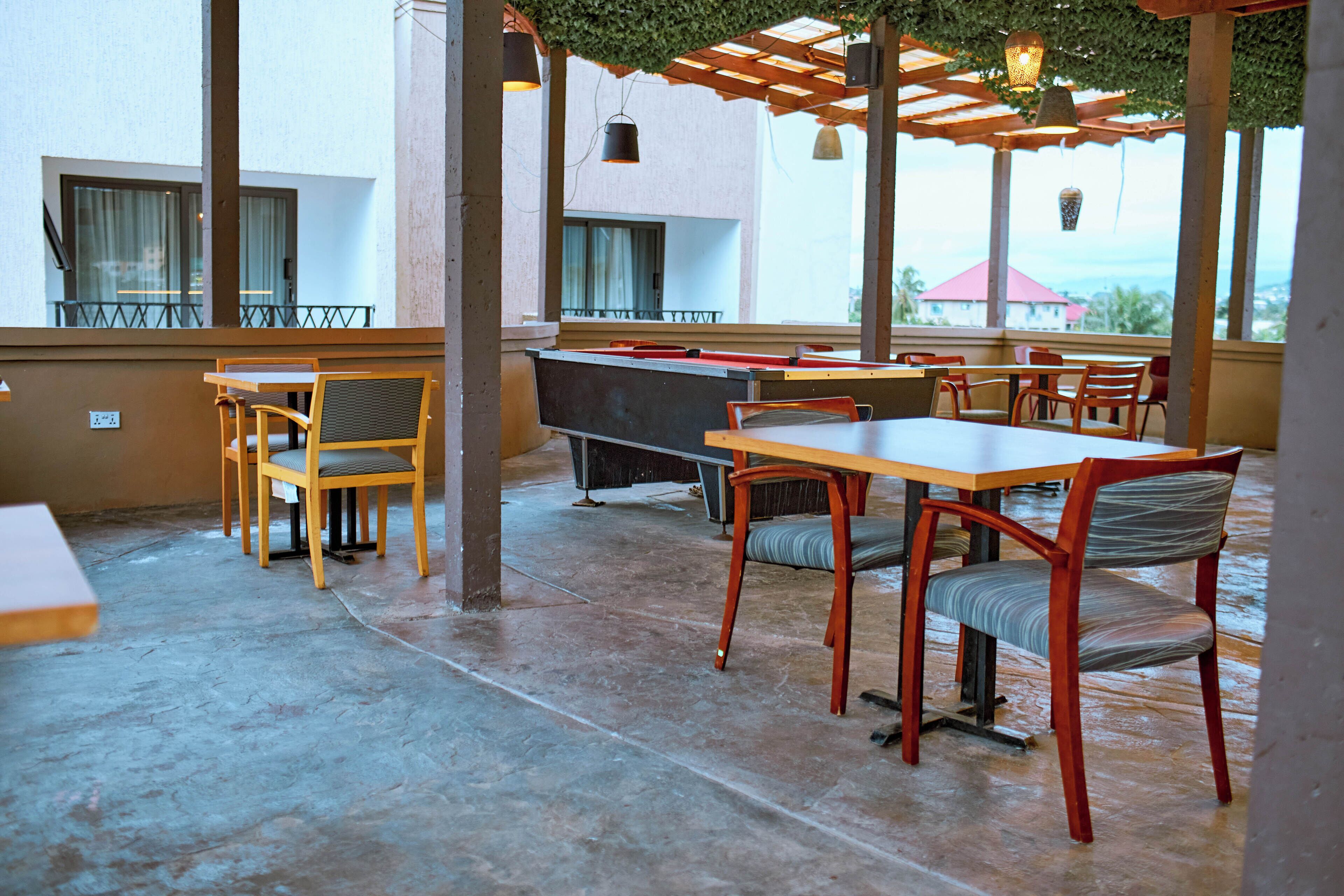 Un espace extérieur abrité, aménagé avec des tables et des chaises, un bar et offrant une vue sur l’océan.