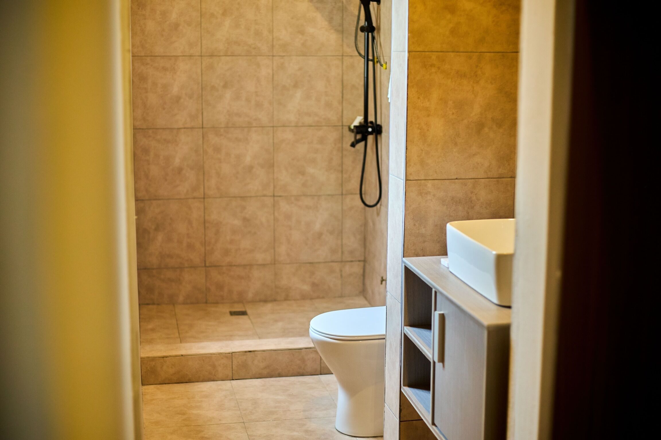 A bathroom with a shower, toilet, and a sink area.