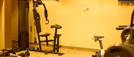 Un gimnasio en casa con equipo de ejercicio, que incluye una cinta de correr, bicicleta estática y máquinas de pesas.