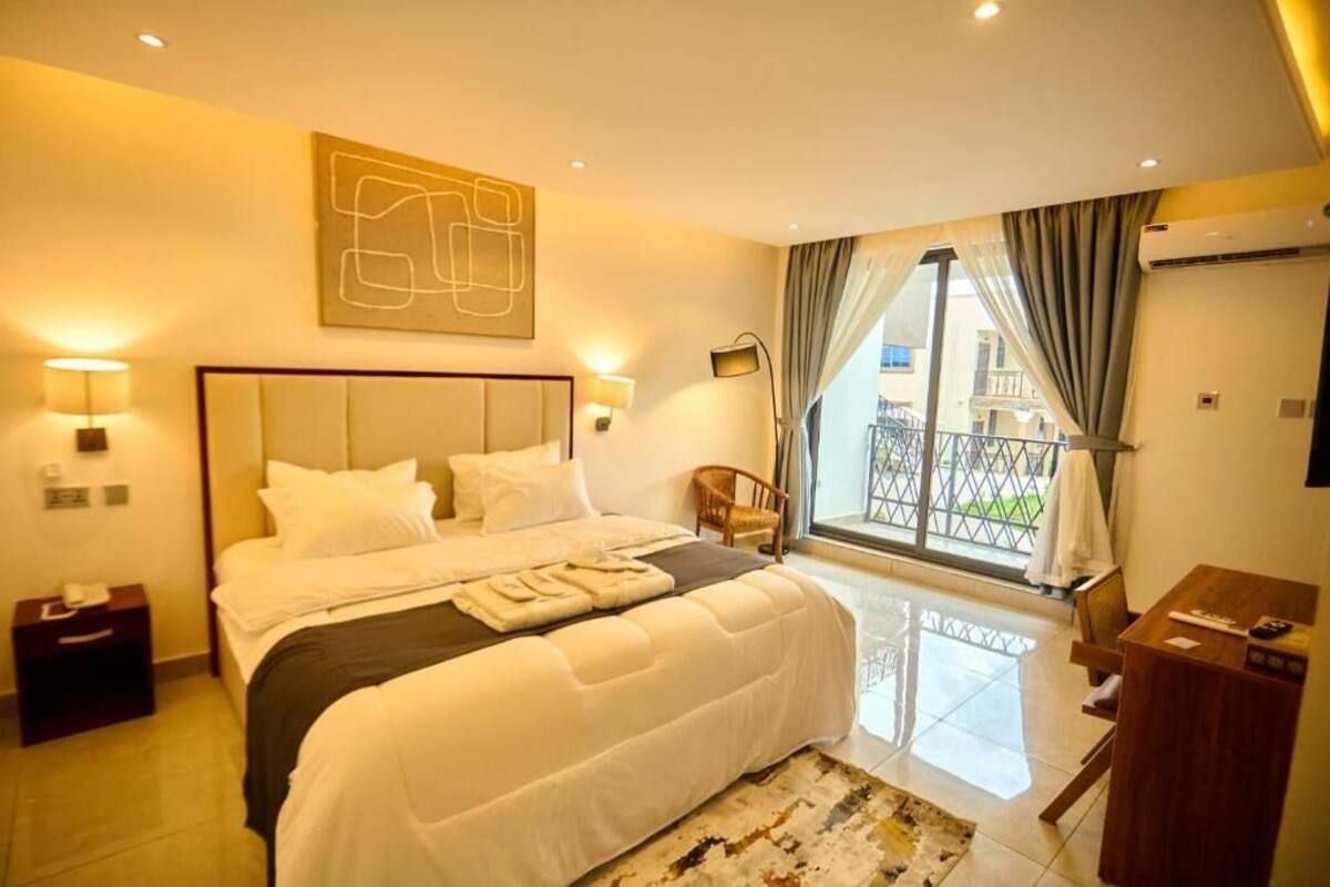 Ein Hotelzimmer mit einem großen Bett, einem Schreibtisch, einem Stuhl und einem Balkon mit Aussicht.