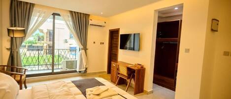 Une chambre d’hôtel équipée d’un lit, d’un bureau, d’une télévision et offrant une vue sur l’extérieur.