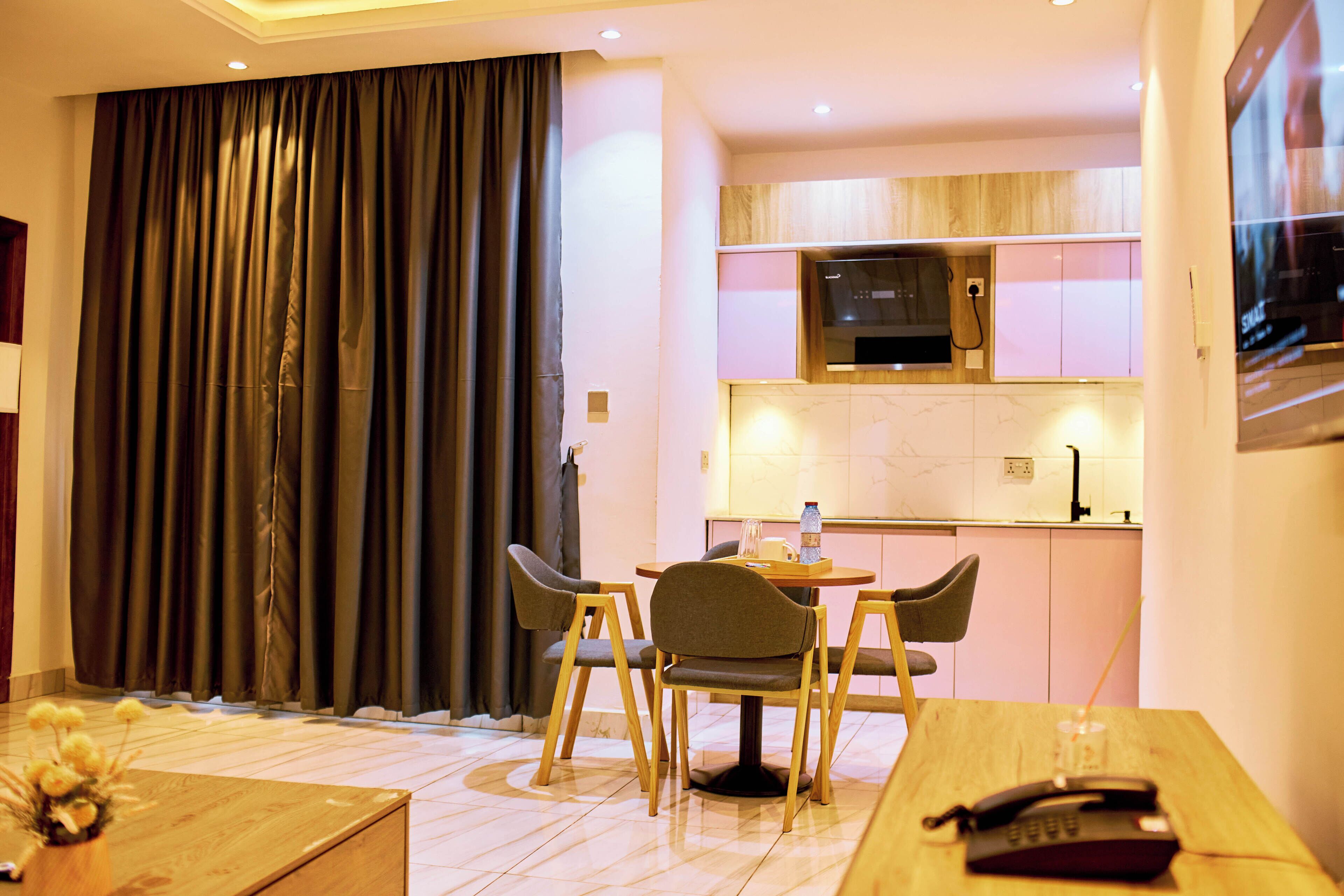 Una habitación de hotel con comedor, cocina y televisor.