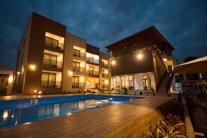 A modern hotel with a swimming pool, multiple balconies, and a well-lit exterior at night. - AIDEN HOMES AND APARTMENTS HOTEL (Koforidua)