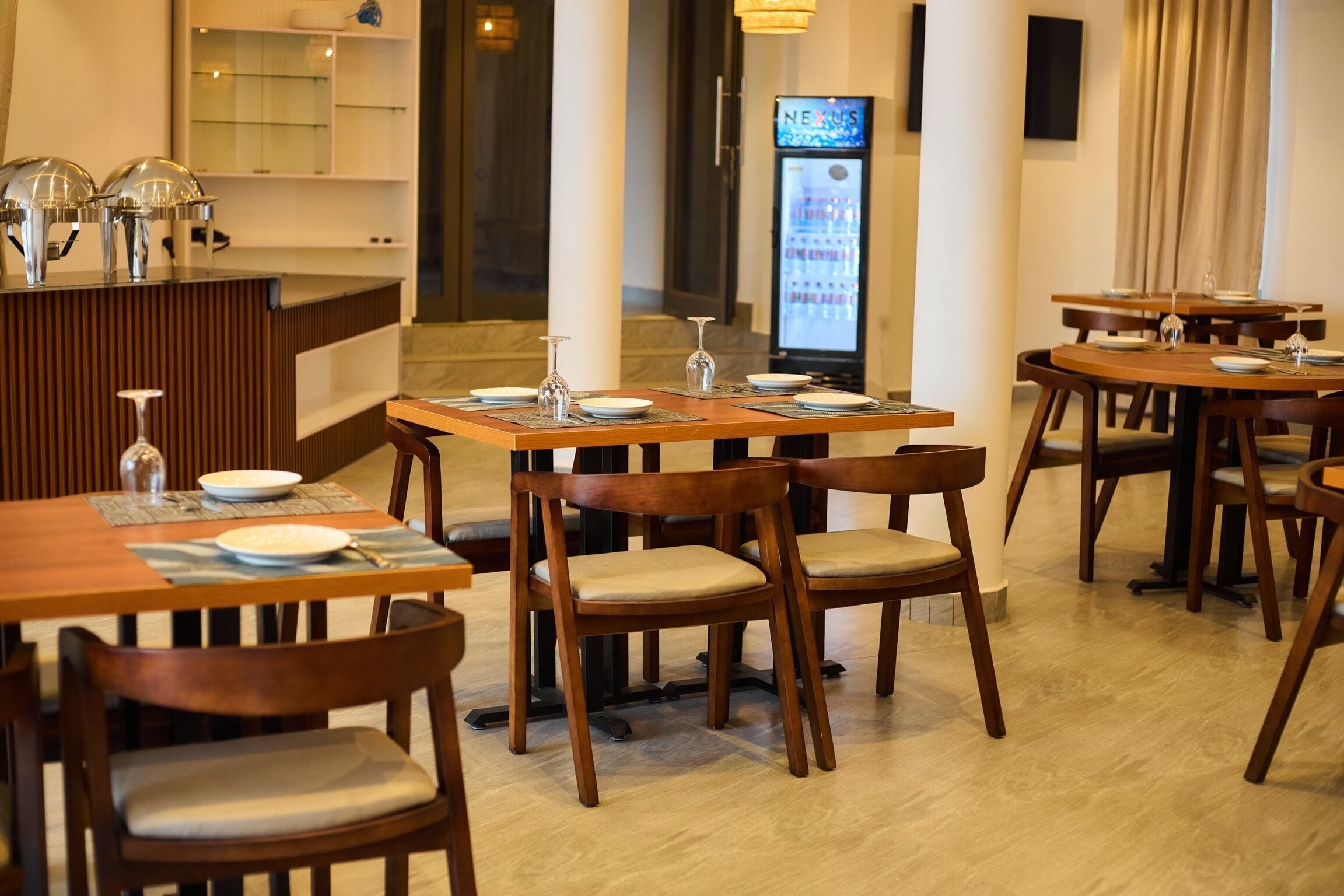 Een restaurant met houten tafels en stoelen, een receptiebalie en een digitaal menubord.