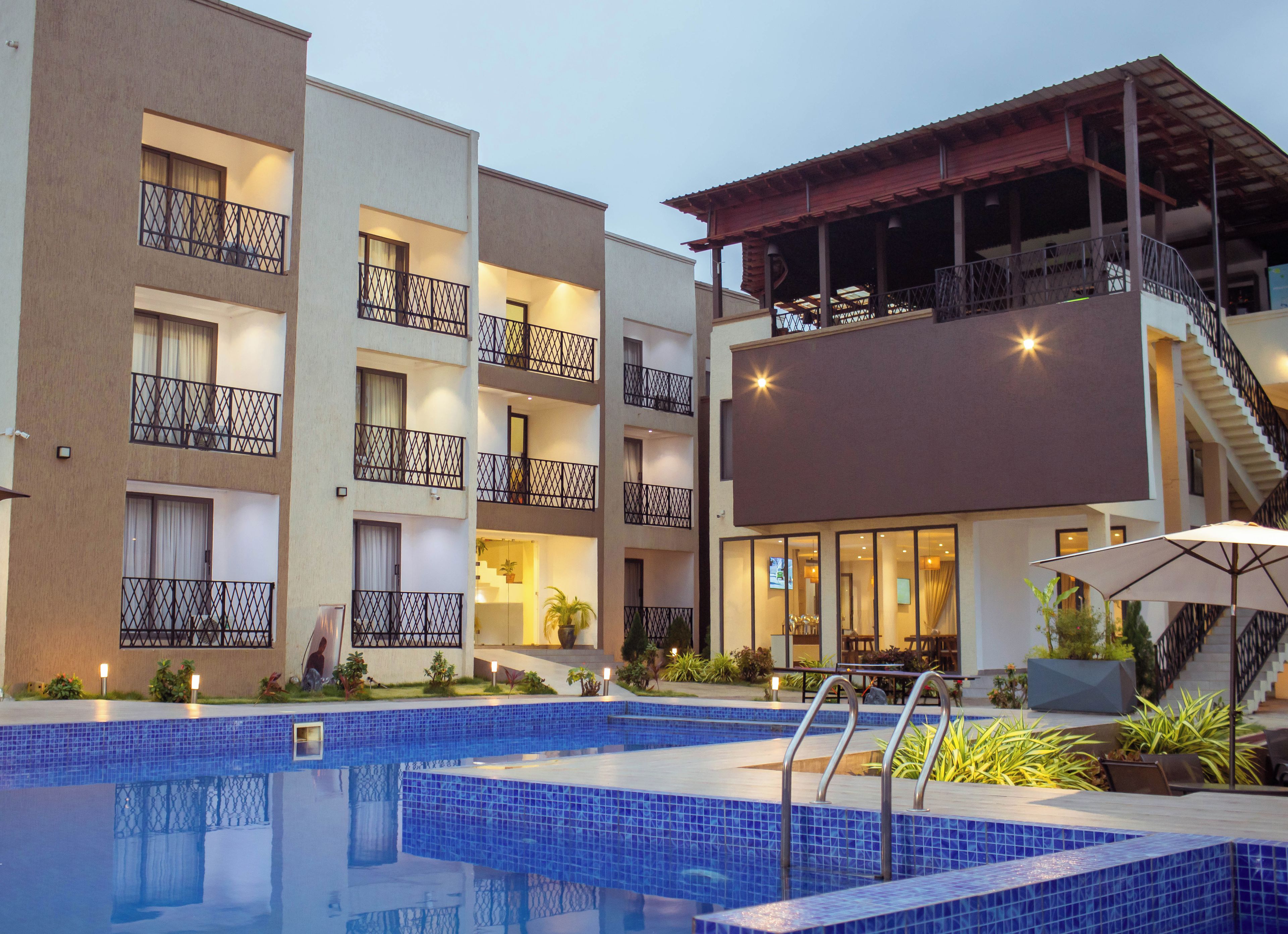 Un hotel con piscina, balcones y un espacio exterior cubierto.