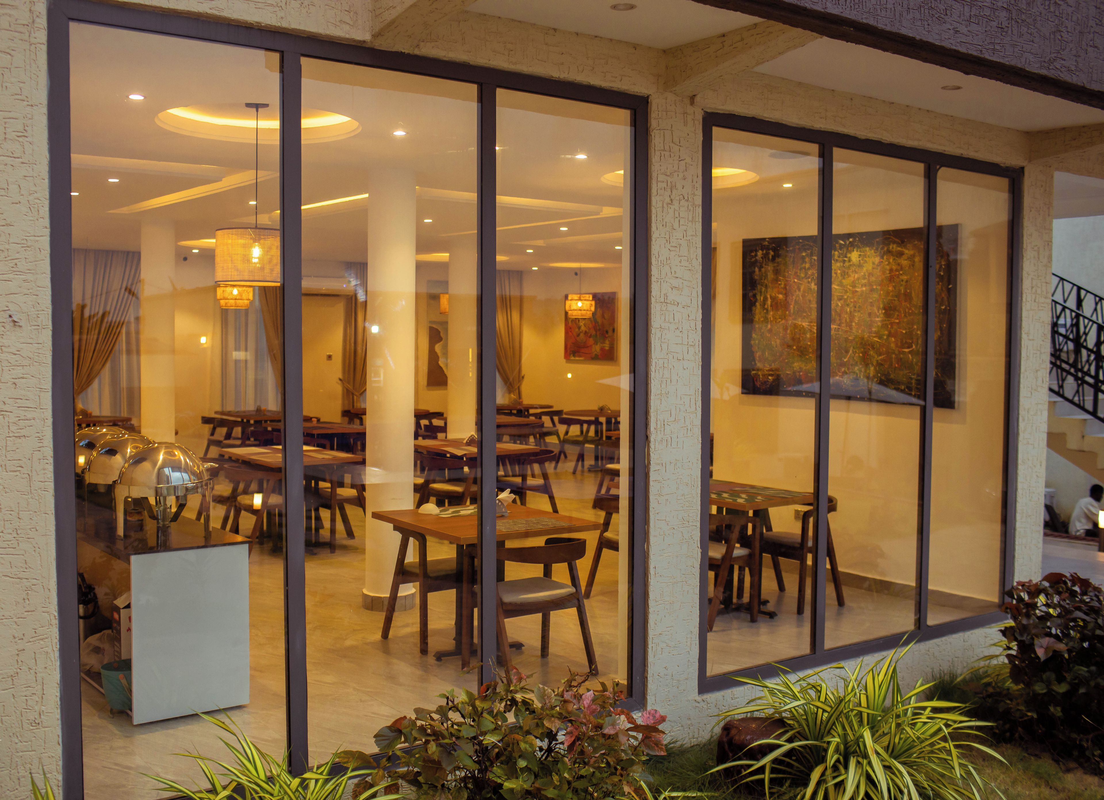A restaurant with a modern interior, featuring wooden tables and chairs, and a large painting on the wall.
