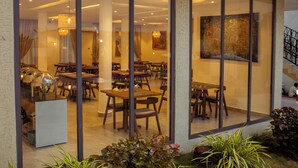 A restaurant with a modern interior, featuring wooden tables and chairs, and a large painting on the wall. - AIDEN HOMES AND APARTMENTS HOTEL (Koforidua)
