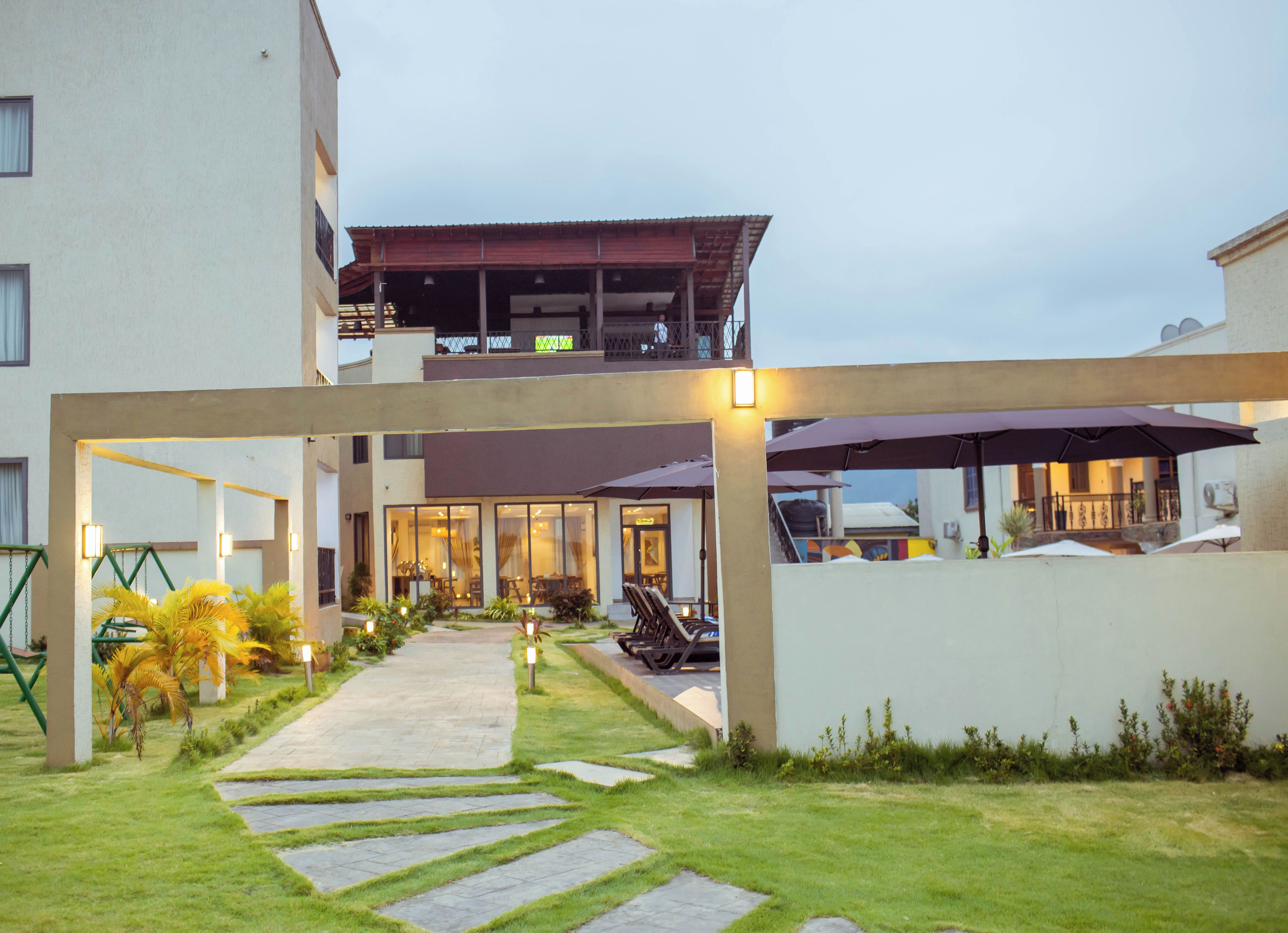 A modern building with a covered outdoor area, a pathway, and outdoor seating.