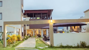 A modern building with a covered outdoor area, a pathway, and outdoor seating. - AIDEN HOMES AND APARTMENTS HOTEL (Koforidua)