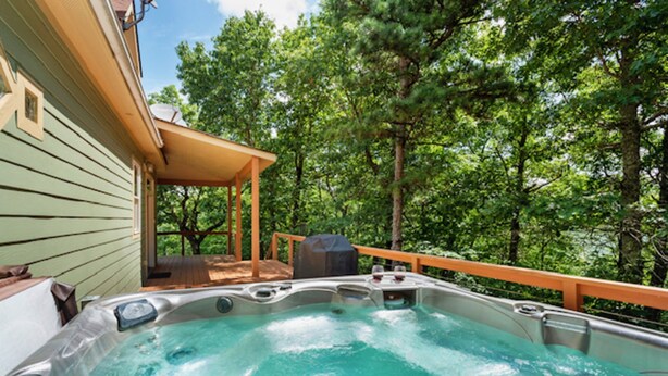 Un jacuzzi en una terraza de madera con vista a un bosque.