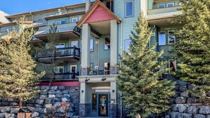 A multi-story hotel with a stone facade, balconies, and a red roof. - Mountain Views | Outdoor Heated Pool | Hot Tub (Canmore)