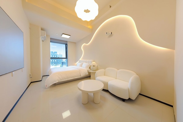 Une chambre moderne comprenant un lit, un canapé et une table ronde, avec un décor mural original et une vue sur la ville.