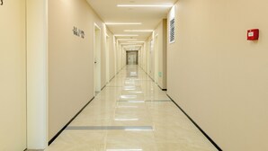 A long, narrow hallway with a shiny floor, doors on the left, and a fire alarm on the right. - Beijing Dream Inn Hotel (Beijing)