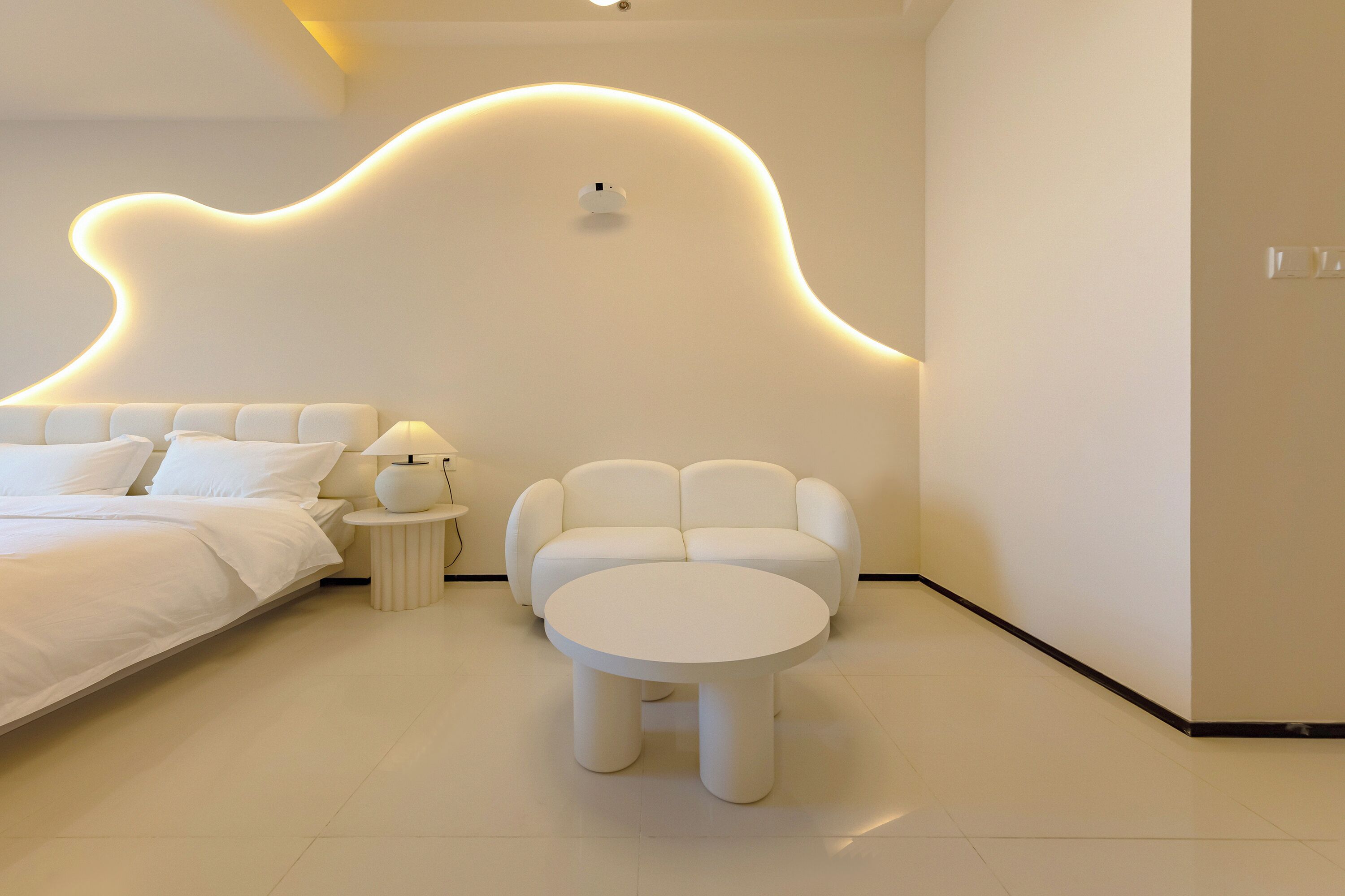 A modern bedroom with a bed, a round table, and a sofa.