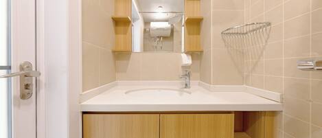 Un baño moderno con lavamanos blanco, armarios de madera y cabina de ducha de vidrio.