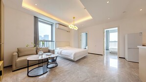 A modern hotel room with a sofa, a bed, a dining table, and a balcony. - Beijing Dream Inn Hotel (Beijing)